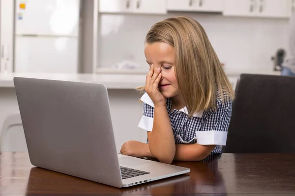 Little girl 6 to 8 years old sitting at home kitchen enjoying with laptop computer concentrated watching internet cartoon movie — Stock Photo, Image