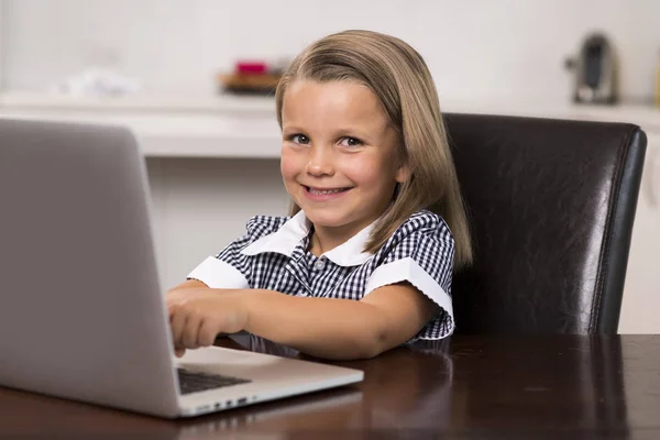 Jovem menina bonita e doce 6 a 8 anos com cabelo loiro e olhos azuis sentados em casa cozinha desfrutando com computador portátil sorrindo feliz — Fotografia de Stock