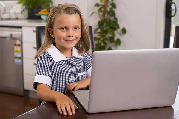 Jovem menina bonita e doce 6 a 8 anos com cabelo loiro e olhos azuis sentados em casa cozinha desfrutando com computador portátil sorrindo feliz — Fotografia de Stock