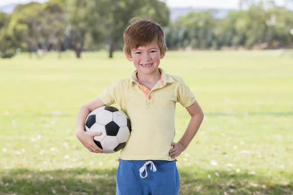 Jonge kind weinig 7 of 8 jaar oud genieten gelukkig spelen voetbal voetbal op gras stad park veld poseren lachende trots staande houden van de bal — Stockfoto
