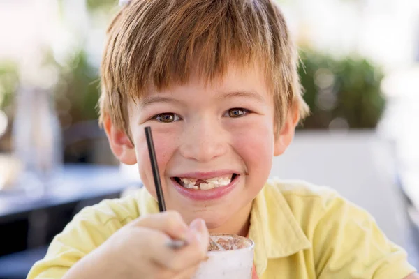 Potret kepala indah dan manis anak muda 7 atau 8 tahun di kemeja kuning menikmati minum es krim smoothie susu shake dengan sendok — Stok Foto
