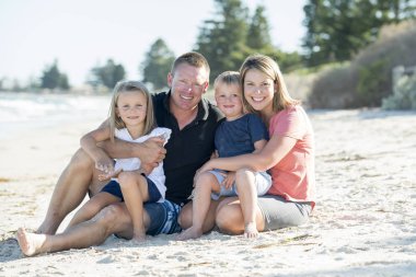 mutlu güzel beyaz aile anne ve babayla kum üzerinde küçük oğlu ve genç kızıyla otururken gülümseyen sahilde tatil sahip