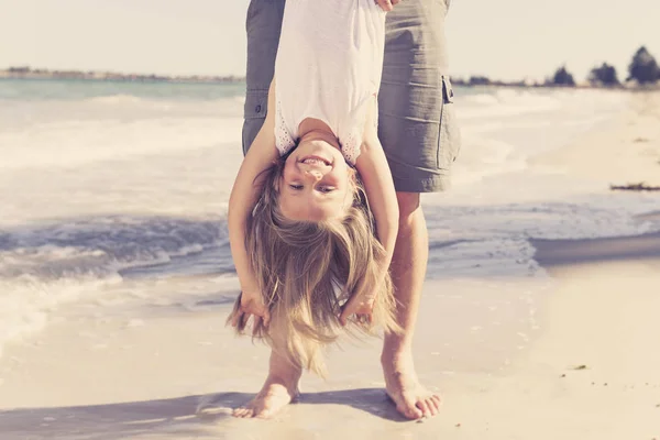 父亲抱着甜美的年轻可爱的金发碧眼的小女儿, 她的脚玩在海滩上的乐趣在爸爸和小女孩的爱概念 — 图库照片