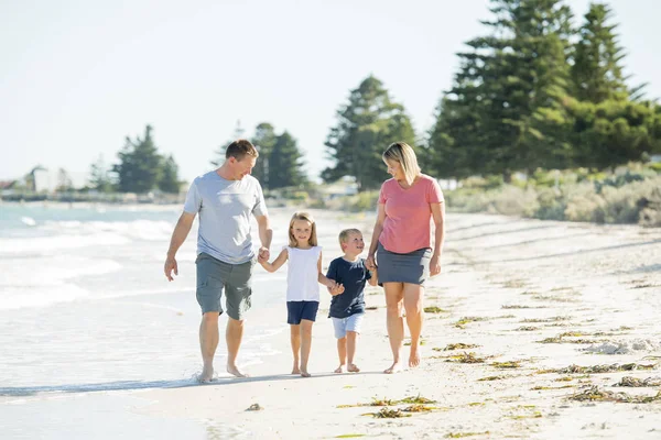 年轻的快乐和美丽的家庭母亲牵手的儿子和女儿漫步在海滩上享受暑假快乐 — 图库照片