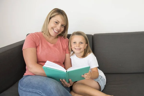 Jeunes belles et heureuses femmes assises avec son adorable 7 ans adorable fille blonde livre de lecture profiter de raconter l'histoire — Photo