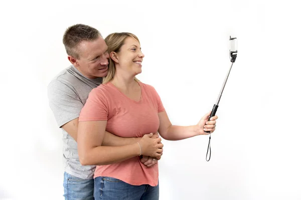 Joven hermosa pareja romántica feliz y atractiva con marido y esposa o novia y novio tomando foto autorretrato selfie con palo —  Fotos de Stock