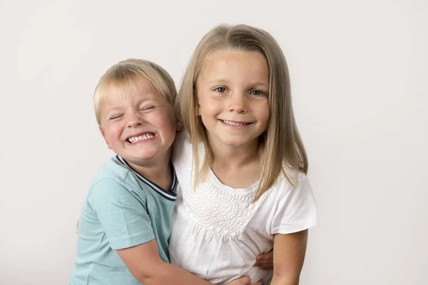 7 years old adorable blond happy girl posing with her little 3 years old brother smiling cheerful isolated on white background — Stock Photo, Image