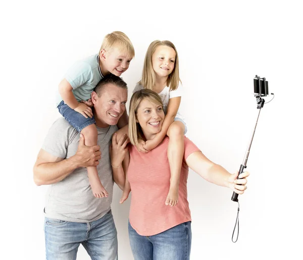 Selfie を取って素敵な若いカップル写真のスティックと幸せな笑みを浮かべてポーズの肩の上の息子と娘を運ぶ携帯電話のセルフ ポートレート — ストック写真