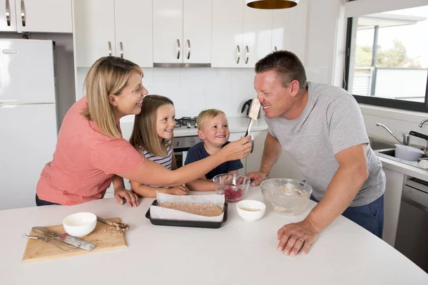 Joven feliz pareja hornear juntos con poco hijo y joven hermosa hija en casa cocina divertirse jugando con crema — Foto de Stock