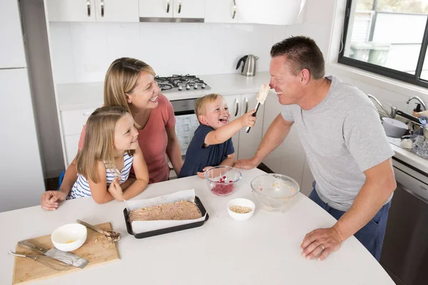 Joven feliz pareja hornear juntos con poco hijo y joven hermosa hija en casa cocina divertirse jugando con crema — Foto de Stock