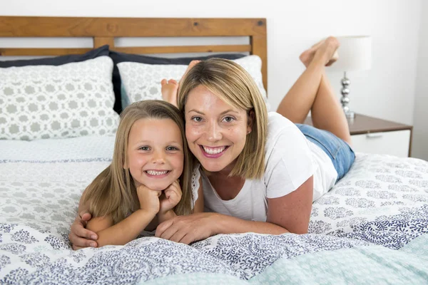 Młoda blond kaukaski kobieta leżąc na łóżku razem z córką młodych słodka i urocza 7 lat stary uśmiechający się zrelaksowany w domu sypialnia — Zdjęcie stockowe