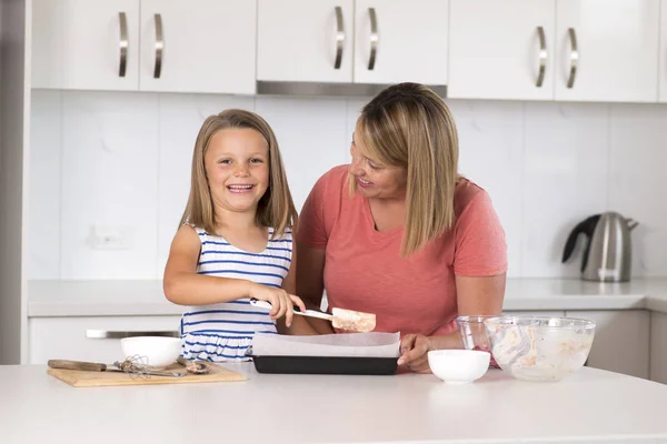 年轻的母亲和甜美的小女儿一起烘烤在家庭生活中快乐家居厨房的概念 — 图库照片