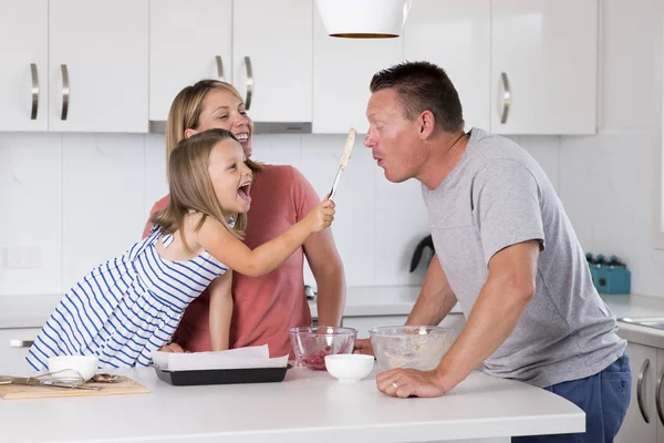 年轻幸福夫妇一起烘烤与小年轻漂亮的女儿在家厨房玩奶油在家庭生活的乐趣 — 图库照片