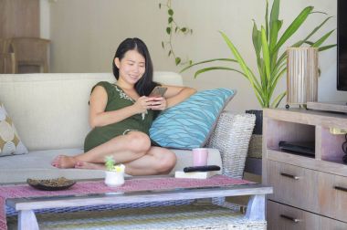 genç güzel ve rahat Asyalı Çinli kadın evde oturma odası kanepe yalan enterne istimal hareket eden telefon mutlu ve rahat kanepe 