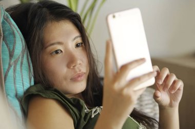 genç güzel ve rahat Asyalı Çinli kadın evde oturma odası kanepe yalan enterne istimal hareket eden telefon mutlu ve rahat kanepe 
