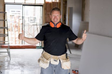 çekici ve kendinden emin Oluşturucu marangoz veya Oluşturucu adam kulak koruma dişli çalışma mutlu endüstriyel inşaat sahasında 