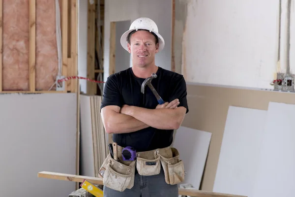 Atractivo y confiado constructor carpintero o constructor hombre en casco protector posando feliz trabajo en la obra de construcción industrial — Foto de Stock