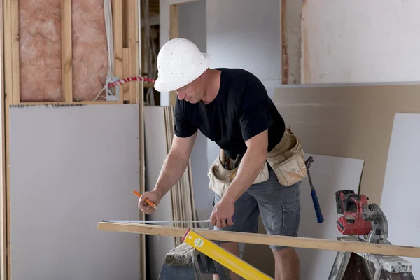 Heureux charpentier constructeur attrayant et confiant ou constructeur homme en casque de protection de travail et de mesure sur le chantier de construction industrielle — Photo