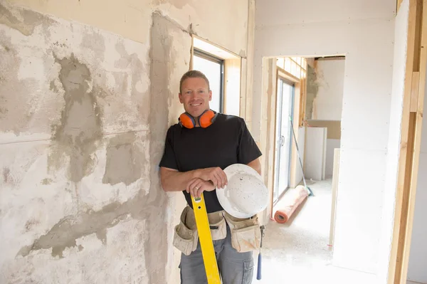 Charpentier constructeur attrayant et confiant ou constructeur homme avec un équipement de protection des oreilles travaillant heureux sur le chantier de construction industrielle — Photo