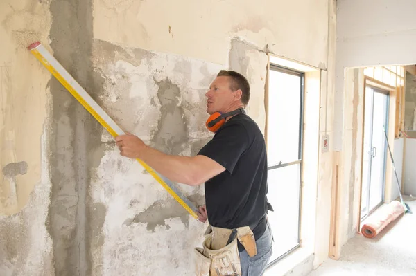 Charpentier constructeur attrayant et confiant ou constructeur homme avec un équipement de protection des oreilles travaillant heureux sur le chantier de construction industrielle — Photo