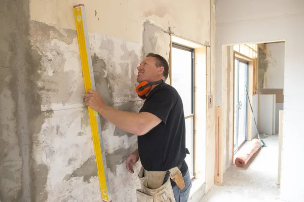 Portrait de jeune homme de chantier attrayant travaillant mur de mesure et de nivellement confiant avec outil de construction sur le chantier — Photo