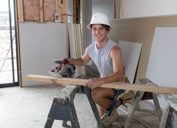 Jeune stagiaire de l'industrie du bâtiment âgé d'une vingtaine d'années portant un casque de protection apprenant à travailler sur le site d'un atelier industriel — Photo