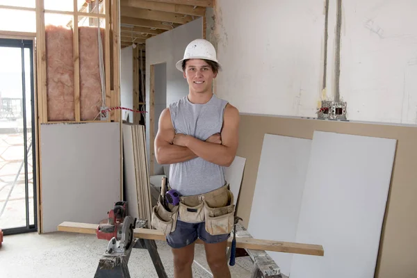 Jeune stagiaire de l'industrie du bâtiment âgé d'une vingtaine d'années portant un casque de protection apprenant à travailler sur le site d'un atelier industriel — Photo