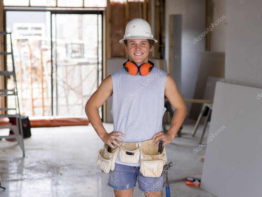 portrait of young attractive builder man on his 20s posing happy confident and proud at construction site wearing protection helmet