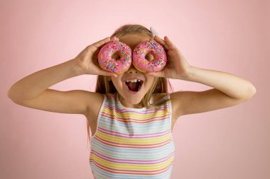 genç güzel mutlu ve heyecanlı sarışın kız 8 veya 9 yaşında gözlerini onları neşeli oynamak arıyorsunuz üzerinde iki donut holding 