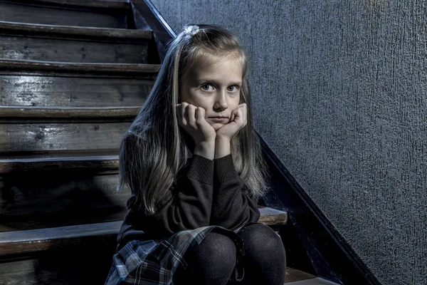 7 oder 8 Jahre altes, deprimiertes und besorgtes Schulmädchen, das verzweifelt und verängstigt auf der Treppe sitzt und Mobbing und Belästigung in der Schule erleidet — Stockfoto