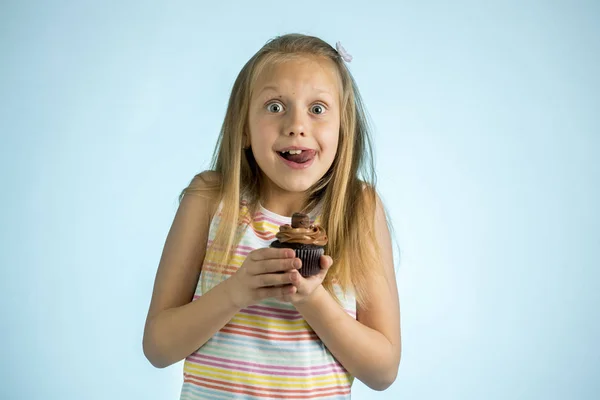 Młody piękny szczęśliwy i podekscytowany blond dziewczyna 8 lub 9 lat gospodarstwa ciasto czekoladowe z jej strony, patrząc, spastyczne i wesoły w koncepcję uzależnienia od cukru — Zdjęcie stockowe