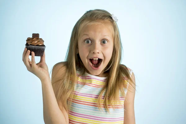 Młody piękny szczęśliwy i podekscytowany blond dziewczyna 8 lub 9 lat gospodarstwa ciasto czekoladowe z jej strony, patrząc, spastyczne i wesoły w koncepcję uzależnienia od cukru — Zdjęcie stockowe