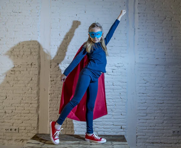 Female child 7 or 8 years old young girl performing happy and excited posing wearing cap and mask in super hero fantasy costume looking playful — Stock Photo, Image