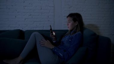 Genç mutlu genç kız ya da kadın üzerinde ev kanepeye geç gece cep telefonunda videocall zevk ve iletişim teknoloji bağımlılığı kavramı içinde app dating internet sosyal medya kullanarak gülümseyen mutlu yalan 20'li