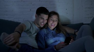 Genç mutlu ve romantik çift birlikte istimal hareket eden telefon oturma zevk onların 20s üzerinde tarama ve eğlenmek internet uygulaması ile internet bağımlılığı kavramında koltuk kanepe Anasayfa