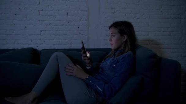 年轻快乐的女孩或女人在她的20S 躺在家里的沙发上深夜快乐的微笑使用互联网社交媒体在手机上享受翻译公司和约会应用程序在通信技术成瘾概念 — 图库视频影像