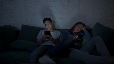Genç çift cep telefonu evde kanepede oturup birbirimizi görmezden yorgun kullanarak kendi 20s üzerinde Internet app iletişim ve akıllı telefon bağımlılık kavramı ilişki eksikliği konsantre