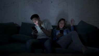 Genç çift cep telefonu evde kanepede oturup birbirimizi görmezden yorgun kullanarak kendi 20s üzerinde Internet app iletişim ve akıllı telefon bağımlılık kavramı ilişki eksikliği konsantre
