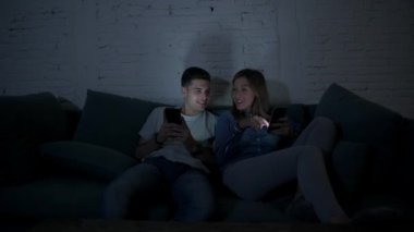 Genç mutlu ve romantik çift birlikte istimal hareket eden telefon oturma zevk onların 20s üzerinde tarama ve Internet app iletişim teknolojisi ve akıllı telefon bağımlılık kavramı ile eğleniyor koltuk kanepe Anasayfa