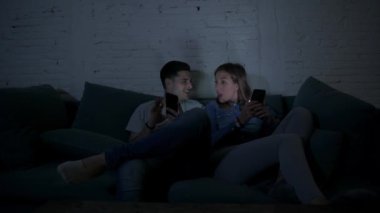 Genç mutlu ve romantik çift birlikte istimal hareket eden telefon oturma zevk onların 20s üzerinde tarama ve Internet app iletişim teknolojisi ve akıllı telefon bağımlılık kavramı ile eğleniyor koltuk kanepe Anasayfa