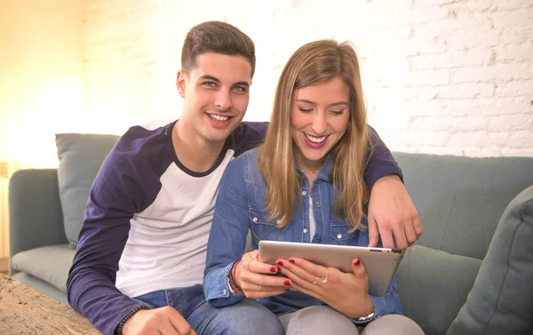 Jovem casal bonito 20s usando tablet digital tablet computador sentado em casa sofá sala de estar compras on-line escolher itens na internet sorrindo feliz — Fotografia de Stock