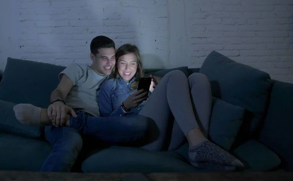 Νεαρό ζευγάρι ελκυστική και ευτυχισμένη χρησιμοποιώντας εφαρμογή internet στο κινητό τηλέφωνο απολαμβάνοντας και γέλιο μαζί να κάθονται στο σπίτι σαλόνι καναπέ-κρεβάτι — Φωτογραφία Αρχείου