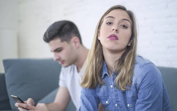 Jovem casal atraente em problema de relacionamento com internet telefone celular vício namorado ignorando triste negligenciado e preocupado namorada em casa — Fotografia de Stock