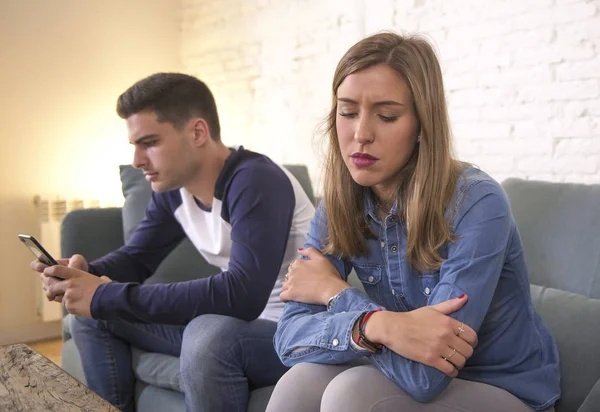 Young attractive couple in relationship problem with internet mobile phone addiction boyfriend ignoring sad neglected and worried girlfriend at home — Stock Photo, Image