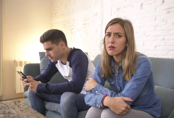 Young attractive couple in relationship problem with internet mobile phone addiction boyfriend ignoring sad neglected and worried girlfriend at home — Stock Photo, Image