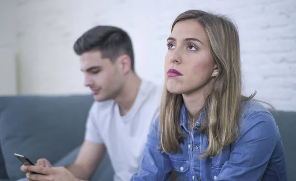 Young attractive couple in relationship problem with internet mobile phone addiction boyfriend ignoring sad neglected and worried girlfriend at home — Stock Photo, Image