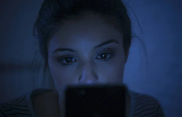 Potret wanita latin muda yang cantik menggunakan ponsel larut malam tanpa tidur berbaring di tempat tidur dalam gelap di smartphone dan internet kencan kecanduan aplikasi — Stok Foto