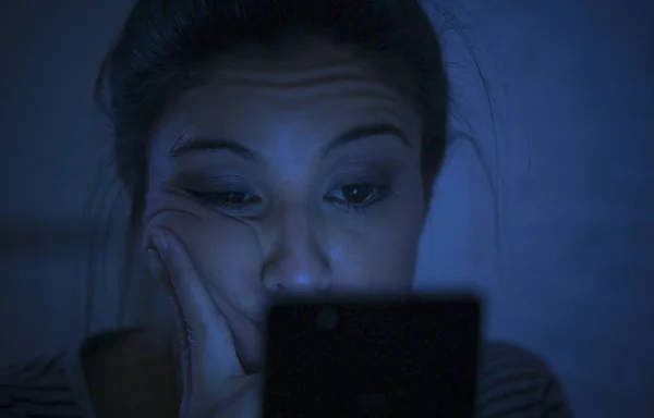 Retrato de la joven hermosa mujer latina utilizando el teléfono móvil tarde en la noche insomnio acostado en la cama en la oscuridad en el teléfono inteligente y la adicción a Internet citas aplicación —  Fotos de Stock