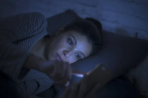 年轻美丽的拉丁妇女的肖像使用手机深夜失眠躺在床上在黑暗中的智能手机和互联网约会应用程序成瘾 — 图库照片