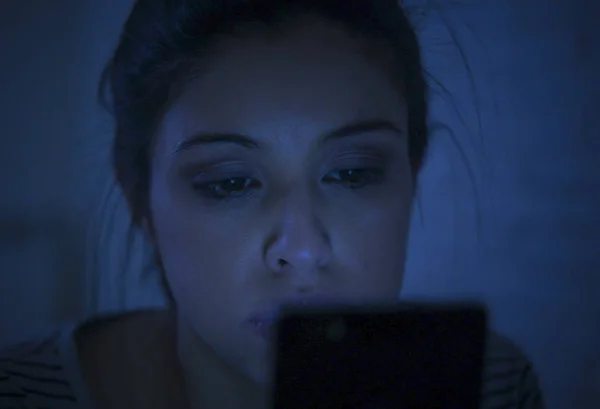 Potret wanita latin muda yang cantik menggunakan ponsel larut malam tanpa tidur berbaring di tempat tidur dalam gelap di smartphone dan internet kencan kecanduan aplikasi — Stok Foto